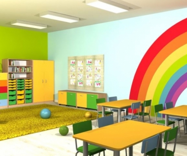 Przedszkole wyposażone w kolorowe meble – stoliki, krzesła, szafę i małe szafki